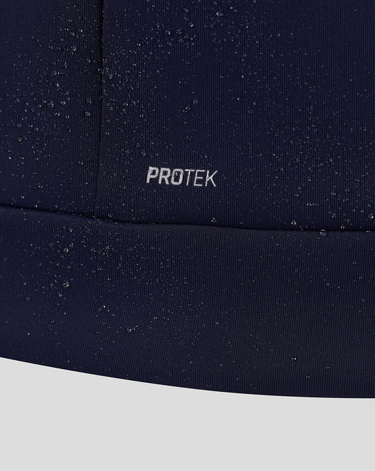 Close-up of navy fabric with PROTEK branding and scattered water droplets.