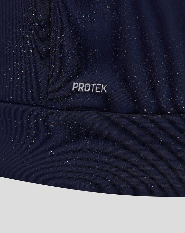 Close-up of navy fabric with PROTEK branding and scattered water droplets.