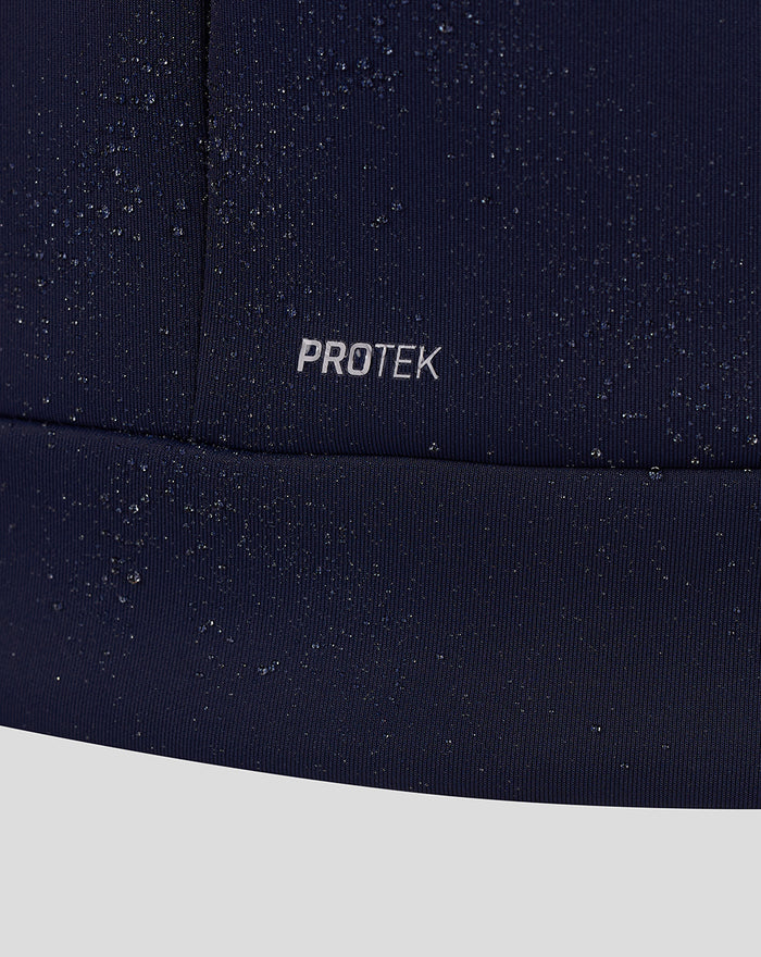 Close-up of navy fabric with PROTEK branding and scattered water droplets.