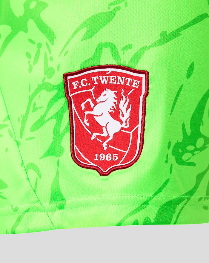 Close-up of red FC Twente crest badge on neon green keeper shorts.