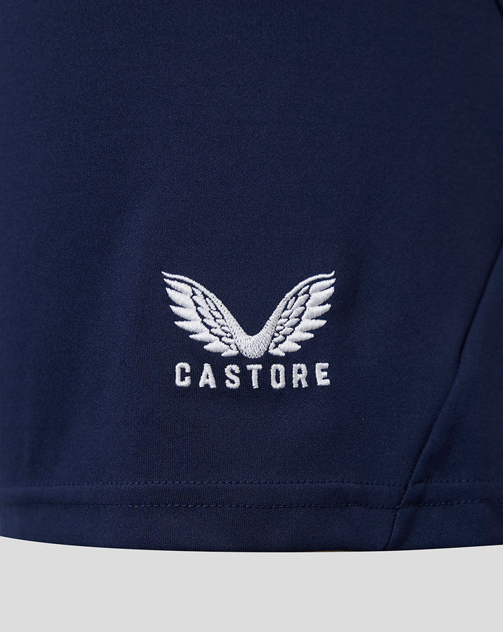 Close-up of navy fabric with Castore logo and wing emblem.
