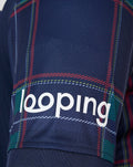 Close up of navy FC Twente fourth shirt fabric with red green tartan pattern and looping branding