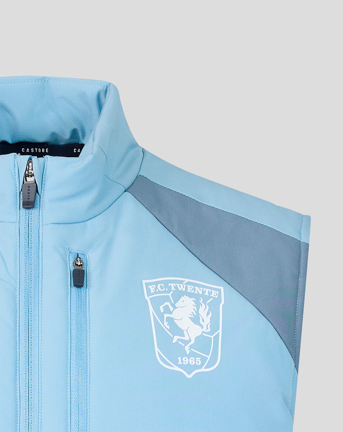 Close-up of the chest area showing the FC Twente crest and zipper on a light blue padded training gilet