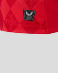 Close up of FC Twente red home shirt fabric with a black Authentic Castore Product badge.