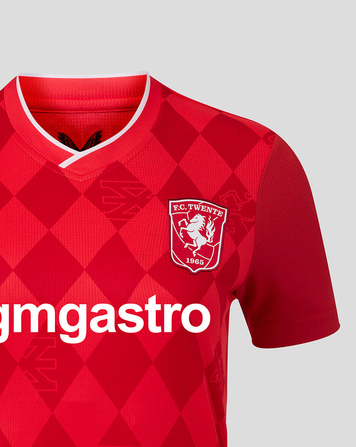 Close-up of FC Twente women's home shirt 25/26 showing red diamond pattern white V-neck collar crest on chest and sponsor across front.