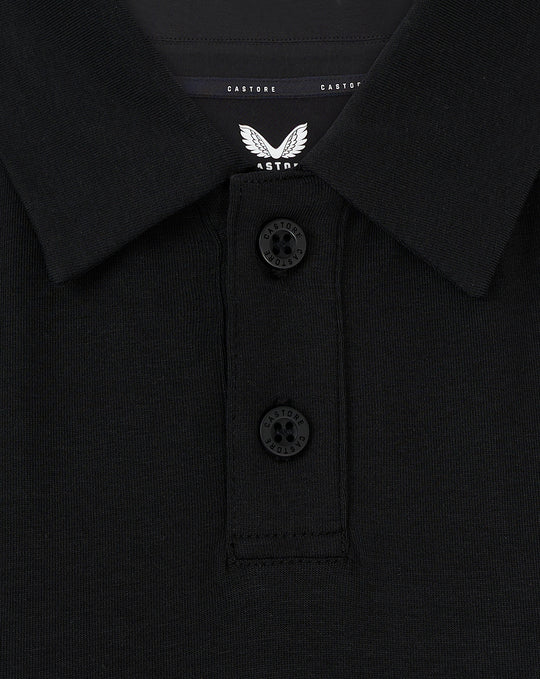 Detail van kraag met twee knopen en Castore label op een zwarte Travel Polo voor vrouwen