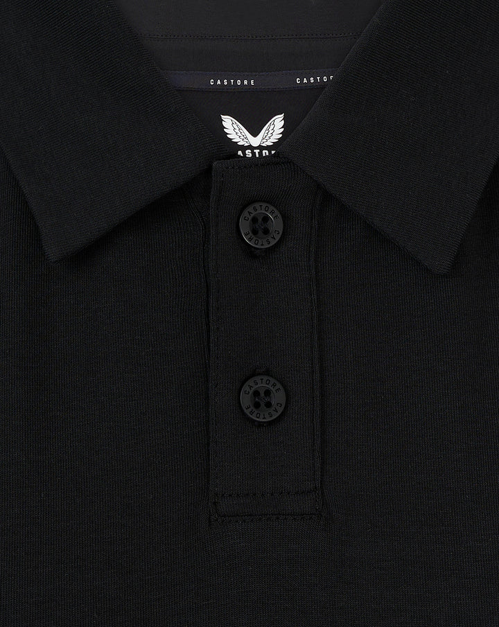 Detail van kraag met twee knopen en Castore label op een zwarte Travel Polo voor vrouwen