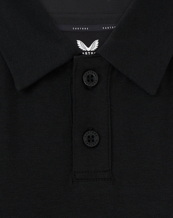 Detail van kraag met twee knopen en Castore label op een zwarte Travel Polo voor vrouwen