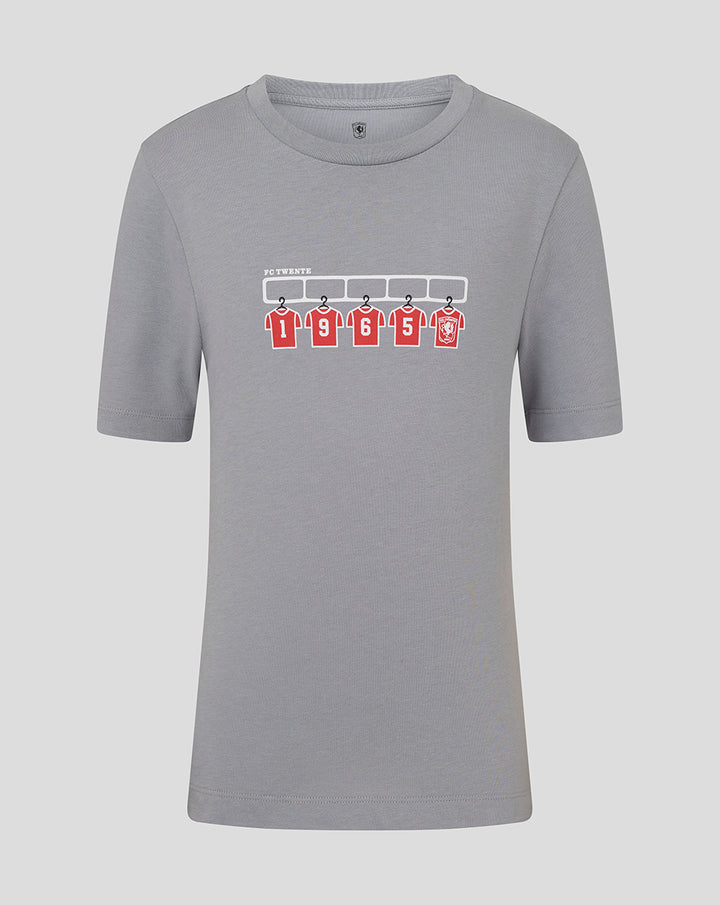 Grey junior FC Twente T shirt with graphic of five red jerseys hanging on a rack.