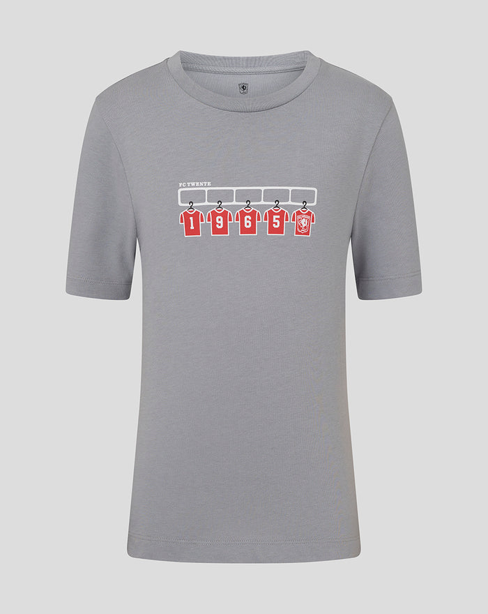 Grey junior FC Twente T shirt with graphic of five red jerseys hanging on a rack.