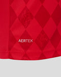 Close up of red FC Twente home shirt fabric with a diamond pattern and AERTEK branding