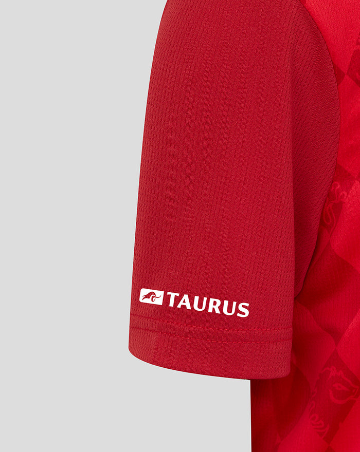 Close-up of the red FC Twente home shirt sleeve with Taurus branding on the cuff and diamond pattern.