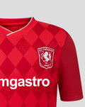 Close up of chest area on FC Twente home shirt 25/26 junior displaying the crest and ggmastro sponsor