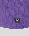 Detail of purple FC Twente junior keepershirt fabric with a textured print and an authentic product patch.