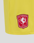 Close up of yellow keeper short showing FC Twente crest on the left leg and curved hem edge.