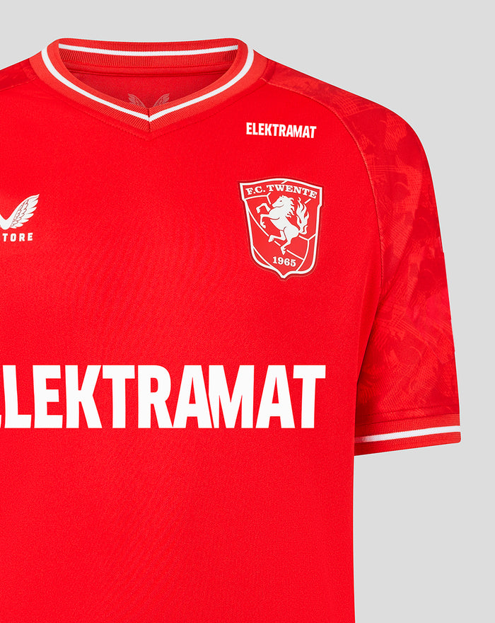 Close-up of the red FC Twente shirt showing crest on the left chest and ELEKTRAMAT across the chest under a white trimmed V-neck.