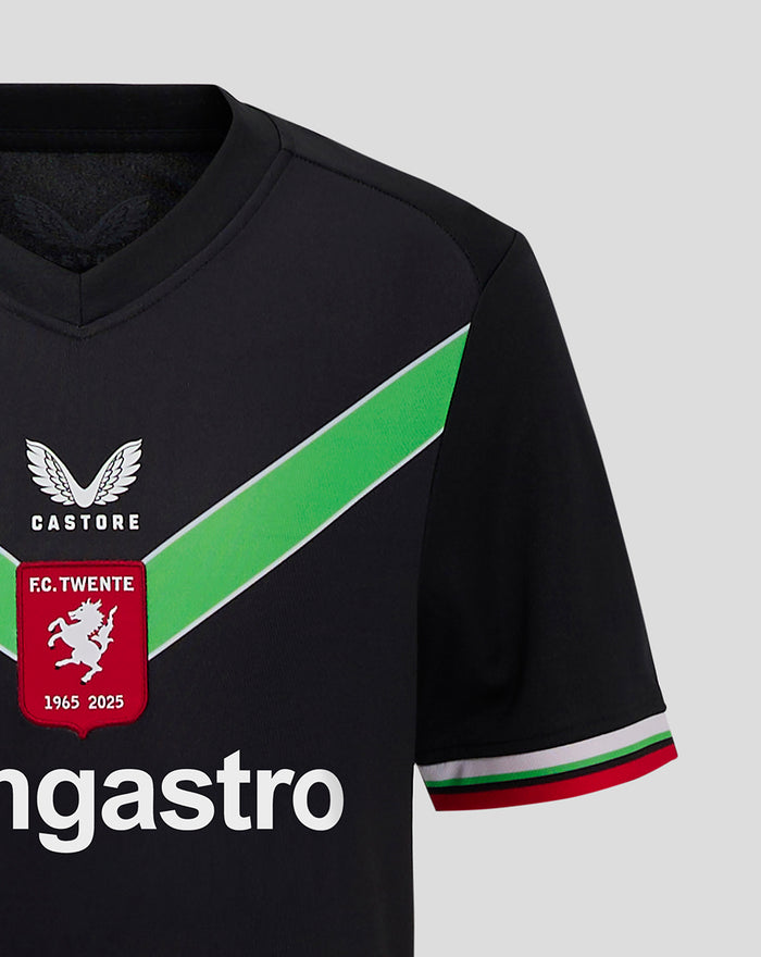 Close up of FC Twente third shirt 25/26 junior with black fabric green diagonal chevron crest and striped sleeve trim.