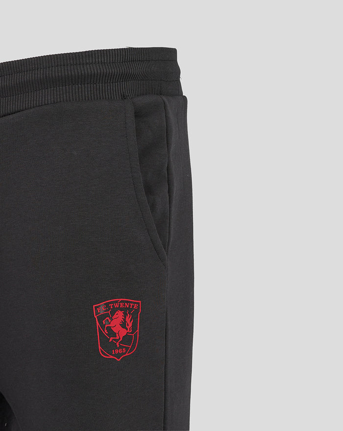 Close up of black junior FC Twente jogger with a red club crest on the thigh near the pocket.