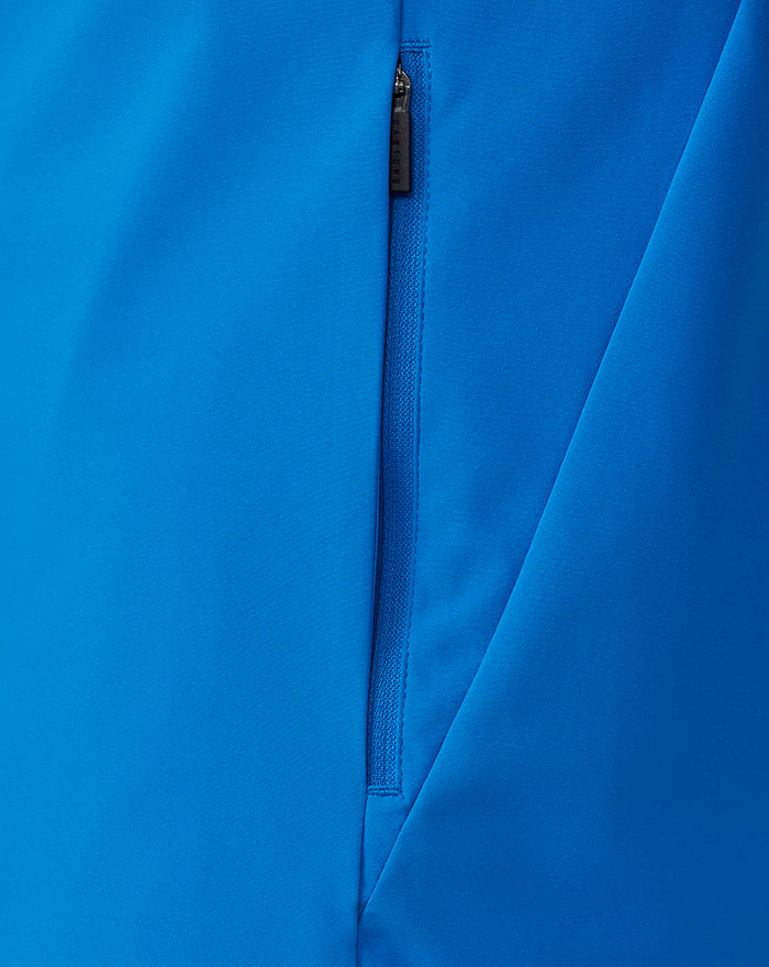 Close-up of bright blue FC Twente rain jacket showing a vertical zipper and smooth fabric.