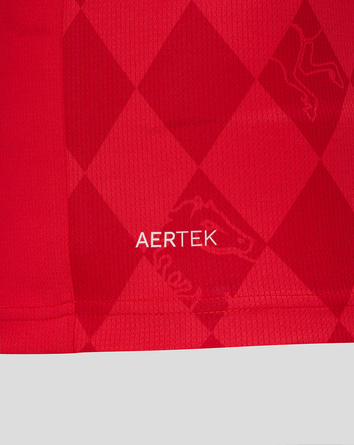Close-up of red Twente home shirt fabric with AerTek branding and subtle diamond pattern