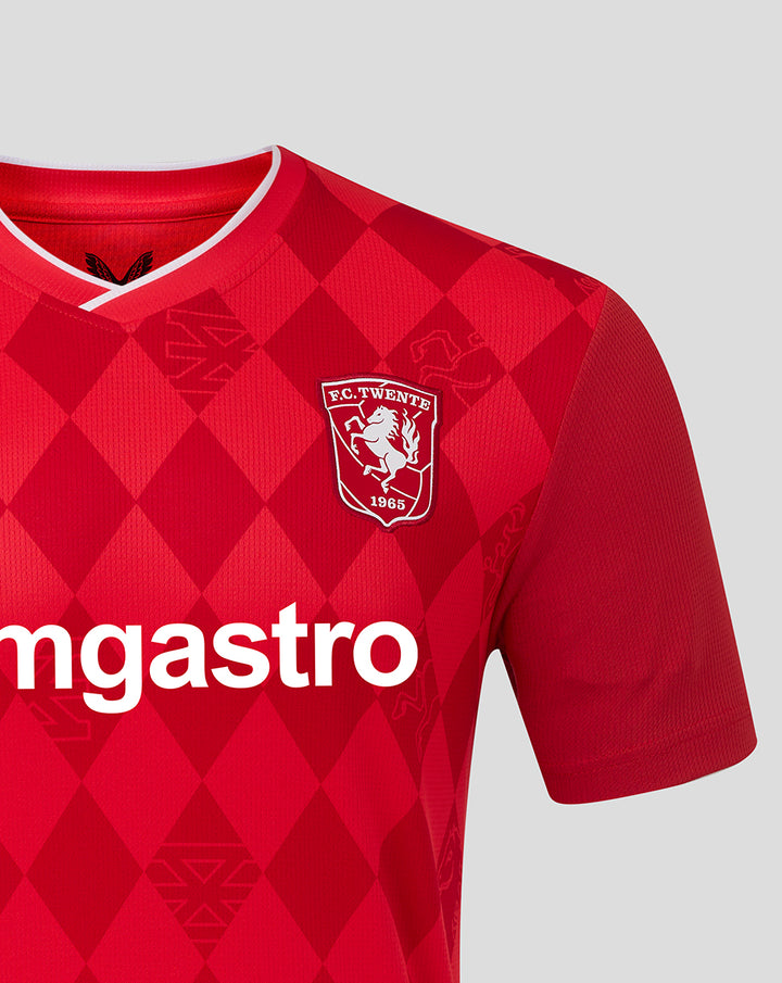 Front chest of red FC Twente home shirt with diamond pattern crest and Castore branding.