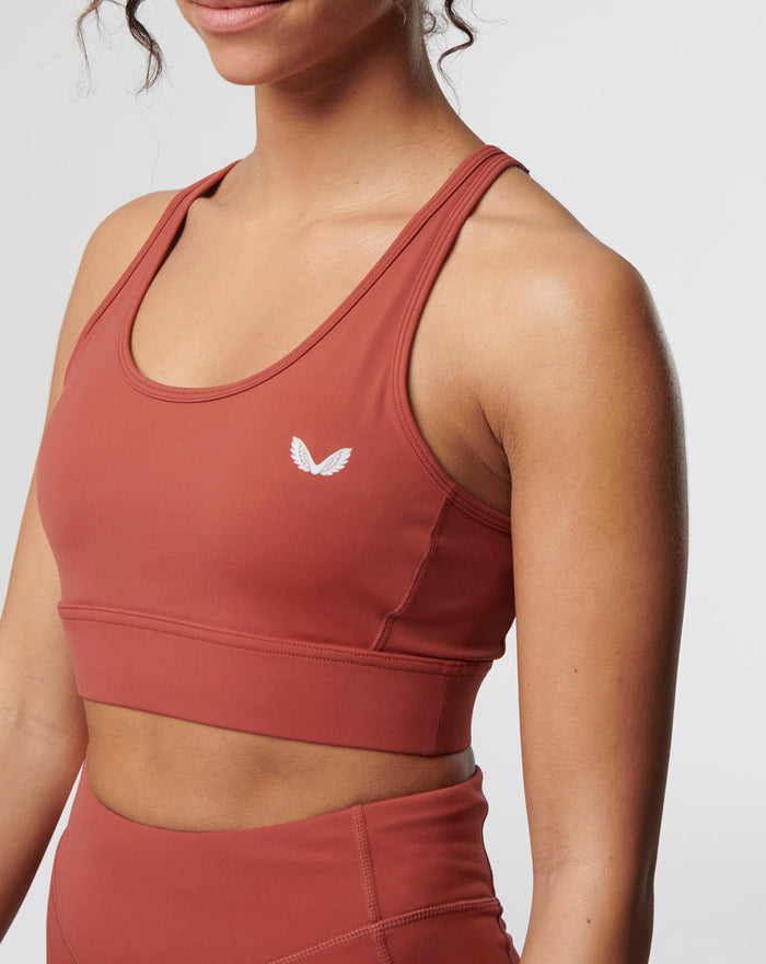 Close-up of the rosewood Active Core Sports Bra showing a small white logo on the chest and double shoulder straps.