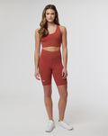 Model wearing rust Rosewood Active Elite Shorts with a matching sports top, front view highlighting the high waist and streamlined athletic fit