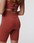 Back view of rust Rosewood Active Elite Shorts showing high waistband seam lines and a Castore logo on the left rear thigh