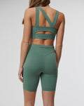 Back view of Sage Active Elite Shorts in teal on a model, showing a deep V waistband, crossback straps and Castore logo on the waistband.