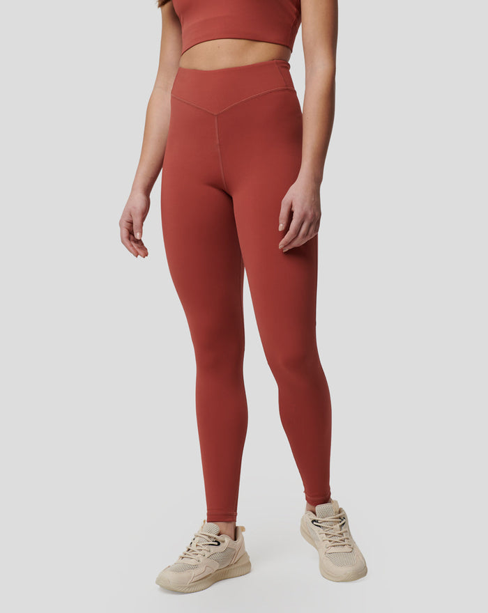 Front view of rust Rosewood Active Air Leggings on a model with calf mesh panels and a high waist, paired with light sneakers.