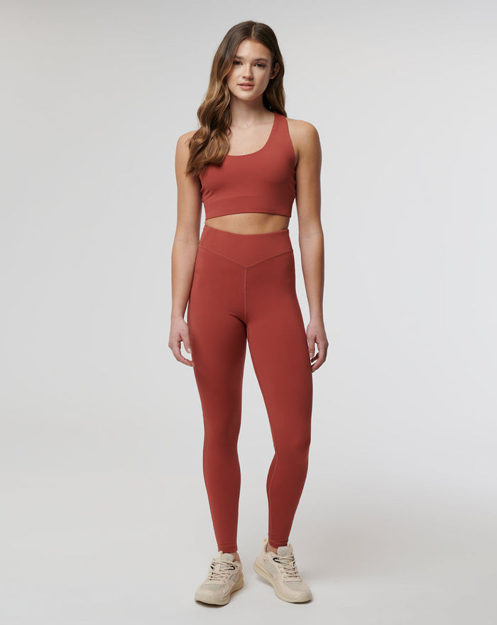 Full body front view of rust Rosewood Active Air Leggings with a matching crop top on a model wearing beige sneakers.
