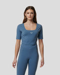 Young woman wearing a blue Carolina Active Contour Crop Top with a square neckline and a small white logo on the chest.