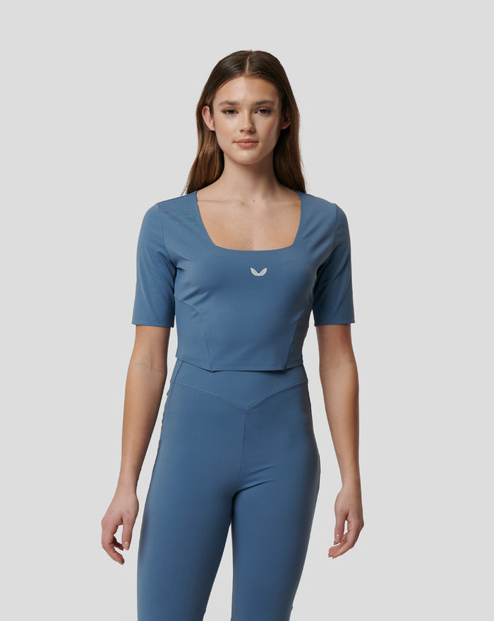 Young woman wearing a blue Carolina Active Contour Crop Top with a square neckline and a small white logo on the chest.