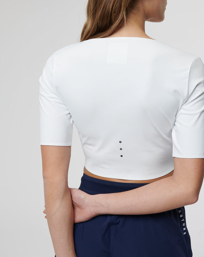 Back view of white cropped top with ventilation holes along the back and a small neck patch