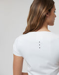 Back view of a white Active Contour Tee showing a vertical row of four ventilation dots along the upper back.