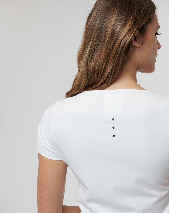 Back view of a white Active Contour Tee showing a vertical row of four ventilation dots along the upper back.