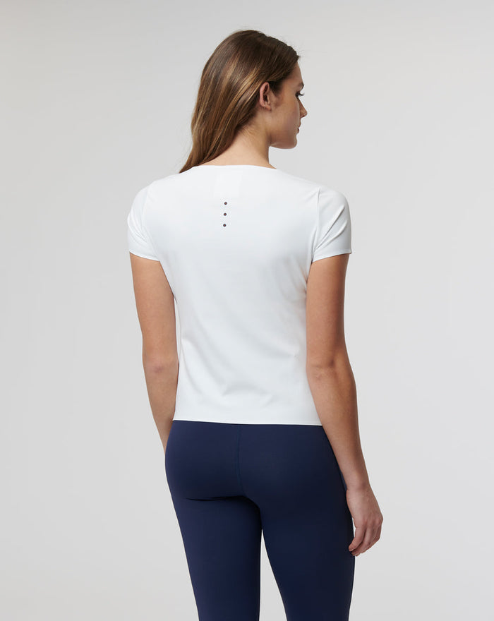 Back view of a woman in a white Active Contour tee showing back vents and fitted seams
