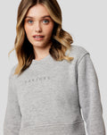 Woman wearing a light grey marl Apex Relaxed sweater with an embroidered Castore Wings logo.