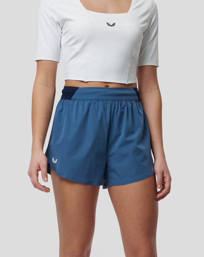 Model wearing white cropped running top and blue Speed Shorts with a mesh back waistband