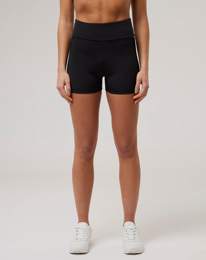 Front view of a model wearing black Onyx BNS Training Shorts with a 3-inch inseam a white side stripe and white sneakers.