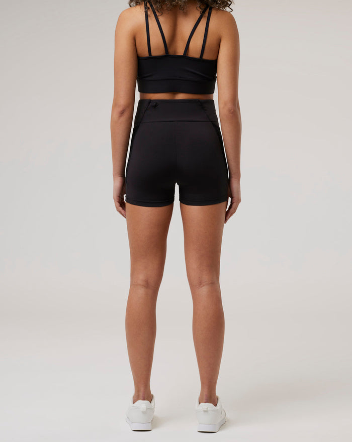 Back view of a model in black Onyx BNS training shorts and sports bra with multi strap back and high waist.