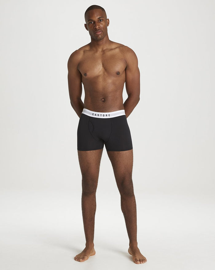 Male model wearing black Castore boxer briefs with white elastic waistband standing against a neutral backdrop.