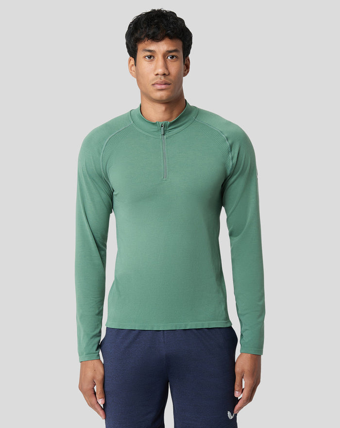 Male model wearing sage green seamless 1/4 zip long sleeve top with high collar.