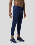 Full-length side view of a male model wearing navy Pace Trousers with elastic waistband and running shoes