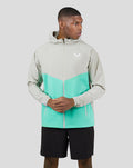 Male model in a turquoise and grey Flyweight Jacket with hood, long sleeves, color blocking and water resistant zips