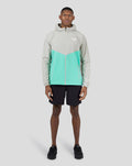 Front view of a male model wearing the Men’s Long Sleeve Flyweight Jacket in turquoise and grey color block.