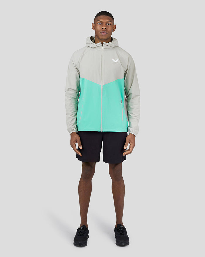 Front view of a male model wearing the Men’s Long Sleeve Flyweight Jacket in turquoise and grey color block.