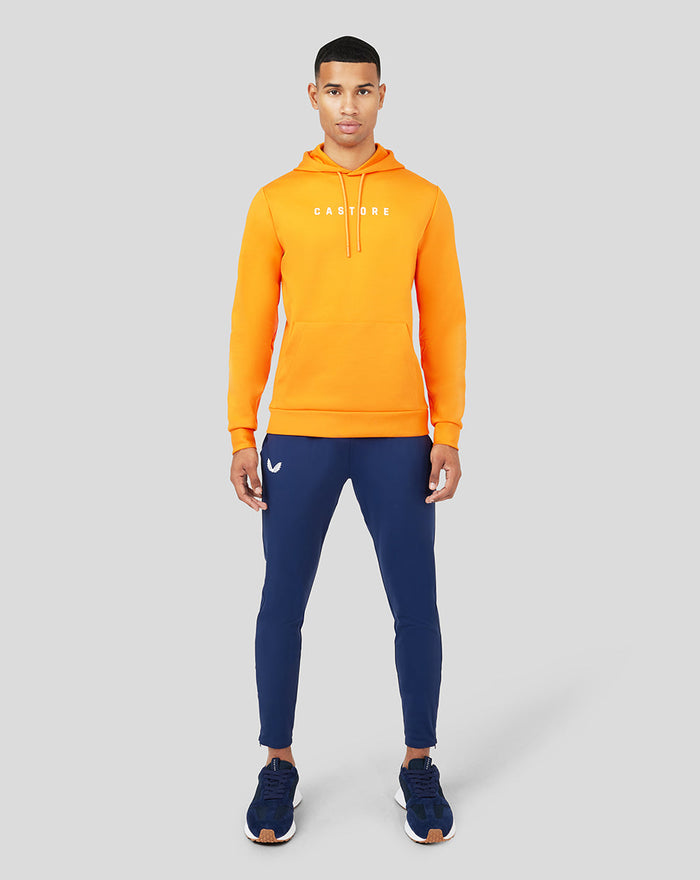 Male model wearing Mandarin Scuba Hoody 3.0 in bright orange with white drawstrings and blue joggers.