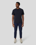 Front view of a man wearing a black Onyx Metropolis Recovery Tee with navy pants and sneakers