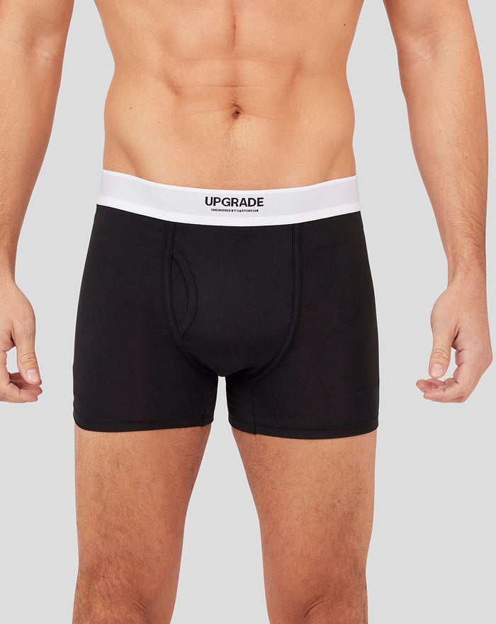 Close up of black Upgrade boxer shorts with a white waistband on a male model.